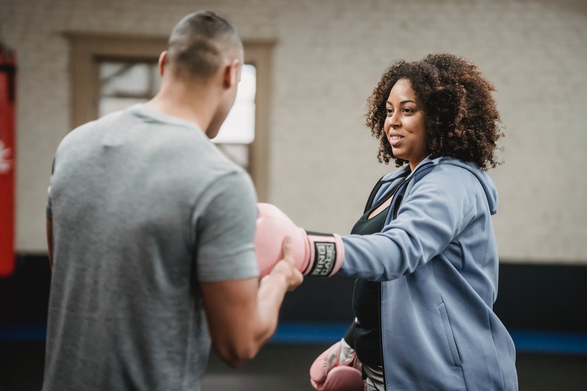 smiling black woman preparing for boxing training with coach